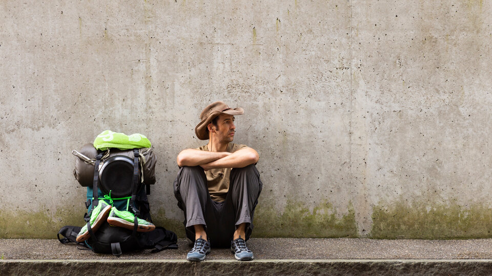 man sitting with a backpack by his side